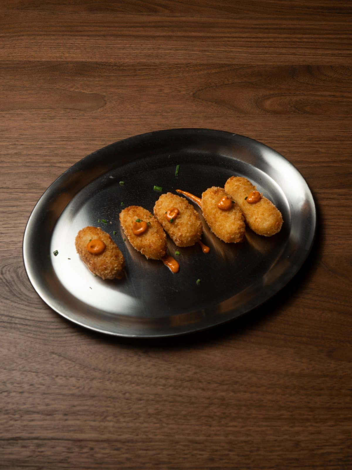 Croquetas de pollo alineadas en plato de acero