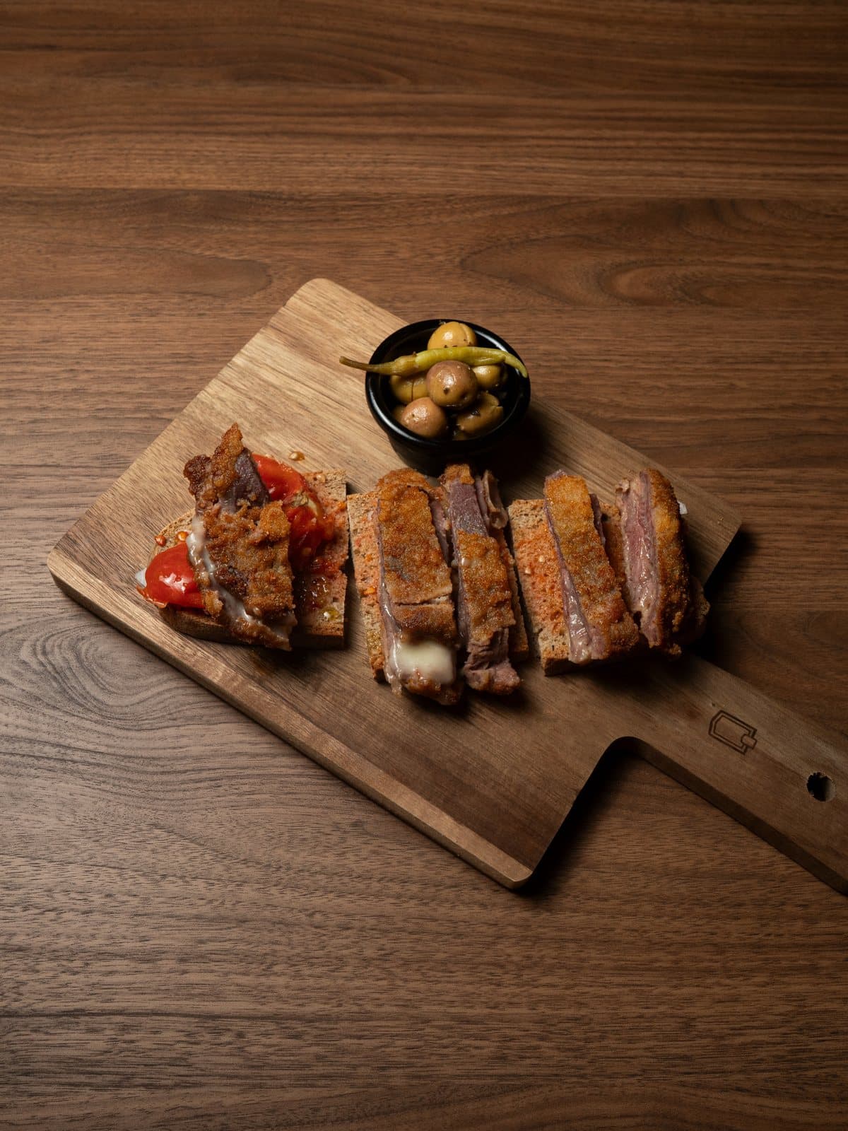 Pa amb oli de cachopo servido en tabla de madera con olivas